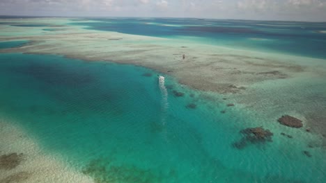 Ein-Einsamer-Kitesurfer-Gleitet-über-Ein-Korallenblaues-Meer-Und-Entfernt-Sich-Von-Der-Kamera,-Luftaufnahme