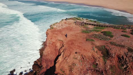 Überflugansicht-Einer-Wanderin,-Die-Mit-Einer-4K-Drohne-Die-Meereswellen-Zeigt,-Die-An-Der-Küste-Des-Surfstrands-Bordeira-In-Der-Portugiesischen-Algarve-Brechen