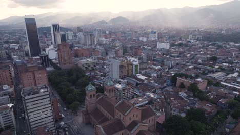 Sun-rays-pierce-clouds-lighting-urban-city-of-Medellin-Colombia-and-Metropolitan-Cathedral-of-Medellin