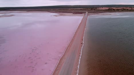 Car-Driving-Through-The-Road-Along-The-Lake-Macdonnell-With-Pink-Water-In-Penong,-South-Australia