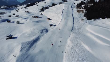 Blue-beginner-ski-piste-in-Alps,-aerial