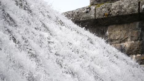 Closeup-of-the-top-of-a-reservoir-dam-weir-with-water-cascading-over-the-top-like-a-waterfall