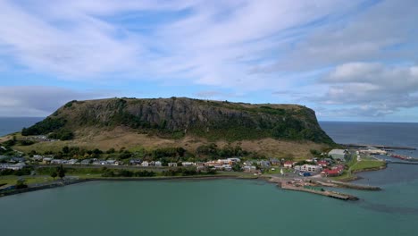 Drone-motion-shot-of-The-Nut-mountain-and-Stanley-coastal-town-with-cloudy-sky-in-Tasmania,-Australia