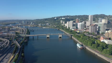 Portland-Oregon,-drone-flying-backwards-over-Willamette-River-revealing-bridge