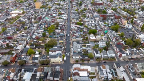 Aerial-hyperlapse-view-of-a-densely-populated-American-city-street-lined-with-tightly-packed-houses-and-busy-traffic