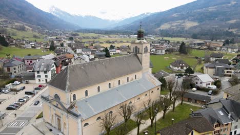 Gran-Iglesia-De-Color-Marrón-Claro-Situada-En-El-Centro-De-Un-Pequeño-Pueblo-En-Las-Montañas-De-Francia