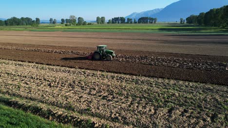 Malerische-Landschaft:-Traktor-Bestellt-Boden-Für-Die-Frühjahrsbepflanzung-Auf-Einem-Schönen-Landwirtschaftlichen-Grundstück-Mit-Buntem-Hintergrund