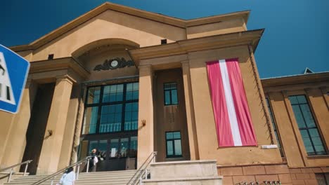 Entrance-of-historic-Daugavpils-train-station-landmark-with-Latvian-flag-banner