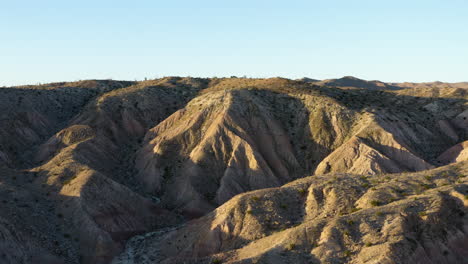 Aerial-footage-retreats,-revealing-the-Badlands,-geological-areas-marked-by-heavily-eroded-rock-formations