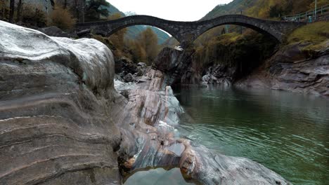 Crystal-clear-water-flows-under-the-bridge-in-Lavertezzo,-Verzasca-valley