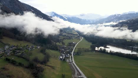 Nubes-Bajas-Sentadas-Sobre-El-Valle-Con-Una-Carretera-En-El-Medio-Y-Rodeada-De-Montañas