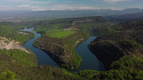 Un-Río-Sinuoso-En-Salvassola-Vic,-Cerca-De-Barcelona,-Exuberante-Vegetación-Y-Fondo-Montañoso,-Vista-Aérea