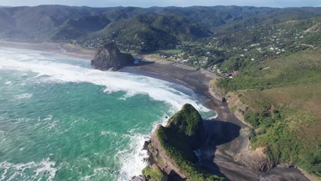 Olas-Rompientes-En-La-Playa-De-Piha-Con-Lion-Rock-Y-Taitomo-Rock-En-La-Región-De-Auckland,-Isla-Del-Norte,-Nueva-Zelanda