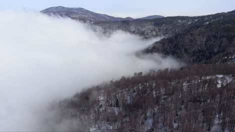 Aerial-view-of-beautiful-mountain-slopes-covered-in-floating-clouds-in-the-forest-winter-day-Kaimaktsalan-Greece