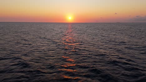 Aerial-dolly-to-hazey-pink-orange-red-sky-reflecting-on-serene-peaceful-waters