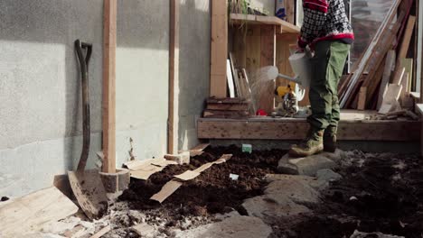 Man-Sprinkling-Soil-With-Seeds-Using-Watering-Can-Inside-The-Greenhouse