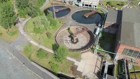 Aerial-view-of-a-wastewater-treatment-plant,-showcasing-circular-sedimentation-tanks-amidst-greenery