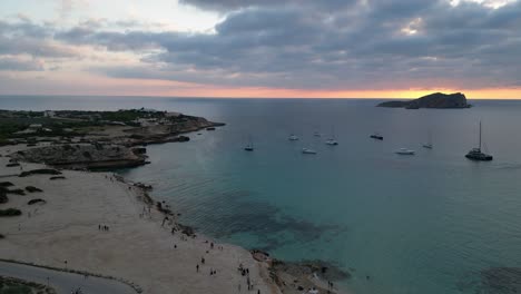 Playa-De-Cala-Comte-Con-Barcos,-Impresionante-Cielo-Al-Atardecer-En-Ibiza