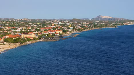 Stunning-deep-blue-tropical-ocean-water-with-coastline-of-Willemstad-Curacao-at-sunset