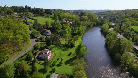 Luxury-houses-along-green-shores-of-Vienne-river-in-Limoges-countryside,-rural-and-idyllic-landscape-of-Nouvelle-Aquitaine-in-France