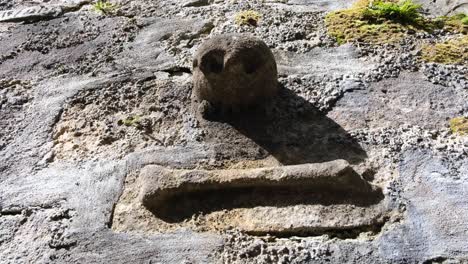 Skull-and-crossbones-carved-from-stone-on-the-outer-wall-of-a-chapel-at-Dunstaffnage-Castle-in-Oban,-Argyll-and-Bute,-Western-Scotland-UK