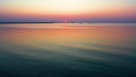 Inicio-Del-Tranquilo-Amanecer-En-El-Océano-Con-Sol-Tenuemente-Iluminado-Sobre-Pequeñas-Islas-En-El-Horizonte