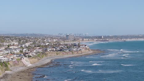 Weite-Luftaufnahme-Der-Felsigen-Küste-Und-Des-Klippenviertels-Von-San-Diego-Mit-Der-Skyline-Der-Stadt-Im-Hintergrund-An-Einem-Sonnigen-Tag
