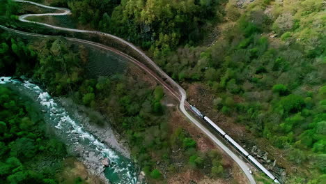 Drone-shot-of-train-traveling-through-Norway's-forested-mountains