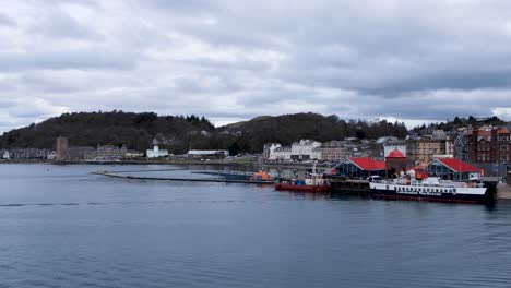 Pan-of-popular-tourist-destination-of-Oban-town,-harbour-and-waterfront-on-a-busy-day-full-of-visitors-on-holiday-and-vacation