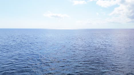 Drone-descends-to-ocean-water-surface-with-beautiful-mesmerizing-tropical-blue-ripples