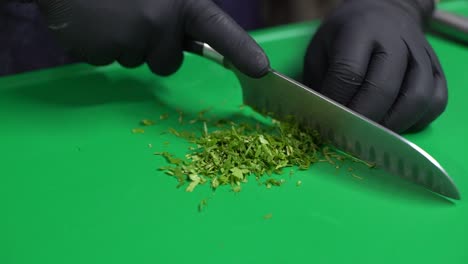 Chef-hands-cutting-parsley-on-green-cutting-board,-close-up