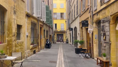 Ruhige-Kopfsteinpflasterstraße-In-Aix-en-Provence-Mit-Historischen-Gelben-Gebäuden-Und-Leeren-Cafés-Bei-Tageslicht