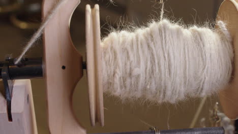 Closeup-scratchy-wool-fiber-spins-into-yarn-on-spinning-wheel-bobbin