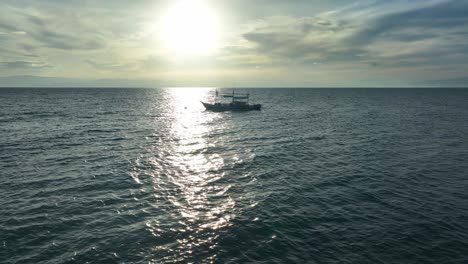 Dron-Acercándose-A-Una-Toma-De-Un-Hermoso-Paisaje-Marino-Y-Un-Barco-Con-El-Sol-Reflejado-En-La-Superficie-Del-Agua