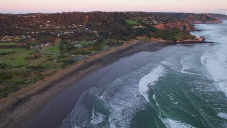 Ocean-Waves-Splashing-Sandy-Shore-Of-Muriwai-Beach,-Auckland-Region-In-The-North-Island-Of-New-Zealand---Aerial-Shot