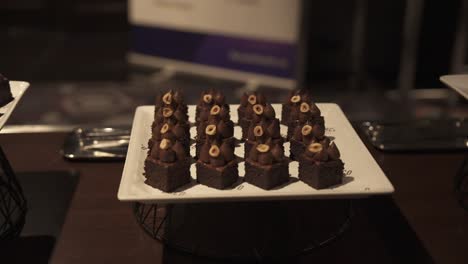 Close-up-of-chocolate-desserts-with-hazelnut-topping-on-a-white-plate-at-an-elegant-event