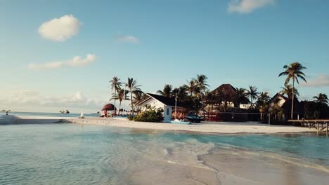 Drohnenvideo-Eines-Tropischen-Resorts-Auf-Den-Malediven,-Niedriger-Flug,-Blaue-Lagune,-Grüne-Palmen,-Sonniges-Wetter,-Sandkasten,-Flaches-Wasser,-4k