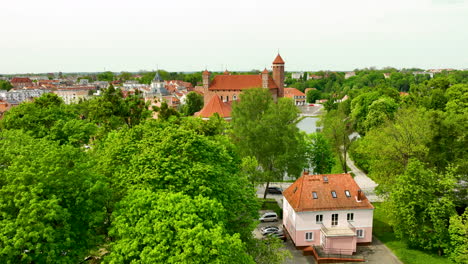 Näherer-Blick-Durch-Das-üppige-Blätterdach-Der-Bäume-Auf-Den-Schlosskomplex,-Der-Die-überragende-Präsenz-Des-Historischen-Bauwerks-über-Den-Modernen-Und-Traditionellen-Gebäuden-Der-Stadt-Zeigt