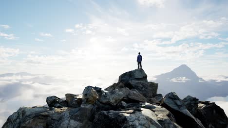 Adventurous-Male-Hiker-Standing-on-Rocky-Cliff-surrounded-by-Mountains