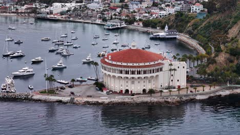 Catalina-island-featuring-the-iconic-avalon-casino-surrounded-by-moored-boats,-aerial-view