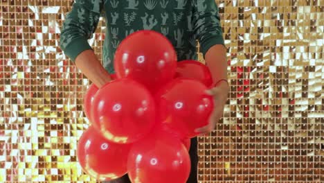 A-male-combining-two-groups-of-red-balloons,-static-closeup