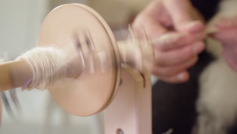 Select-focus-closeup:-Spinning-bobbin-foreground,-hands-in-background