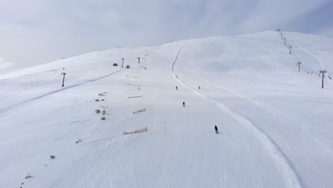 Vista-De-Drones-De-Esquiadores-Esquiando-Cuesta-Abajo-En-Las-Laderas-De-La-Pintoresca-Montaña-Kaimaktsalan-Grecia-Día-De-Invierno