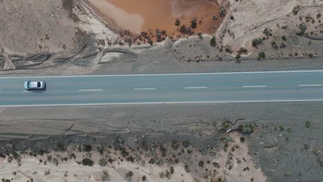 Luftaufnahme-Eines-Autos,-Das-Auf-Einer-Asphaltierten-Straße-In-Einem-Trockenen-Gebiet-Der-Provinz-Jujuy-In-Argentinien-Fährt