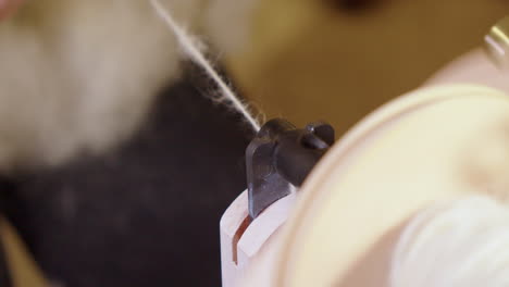 Spinning-wheel-twists-wool-into-yarn,-machinery-narrow-focus-closeup