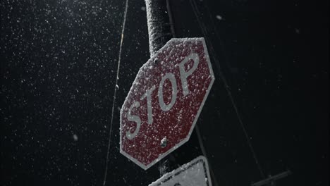 Winter-snowfall-at-night-on-stop-sign-in-city