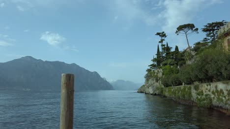 Vista-Del-Lago-De-Garda-Desde-Malcesine,-Que-Muestra-Una-Exuberante-Vegetación,-Montañas-Y-Arquitectura-Histórica.