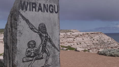 Aboriginal-art-piece-engraved-in-stone-is-placed-on-a-cliff-overlooking-the-ocean