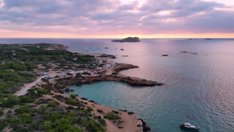Rosa-violetter-Himmel,-Strand-Von-Cala-Comte-Mit-Booten,-Atemberaubender-Sonnenuntergangshimmel-Auf-Ibiza