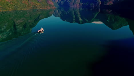 Drone-shot-of-a-boat-sailing-through-Flam's-inlet-in-Norway